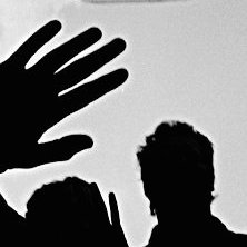 Schwarzweißbild: Foto von einer 1. Mai-Demonstration auf der Kreuzberger Oranienstraße, im Vordergrund die Schatten einiger Demonstranten, im Hintergrund darüber ein im Wind flatterndes Plakat.