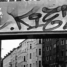 Schwarzweißaufnahme. Drei Frauen stehen vor einem Schaufenster, in dem sich die Fassaden der gegenüberliegenden Häuser spiegeln.